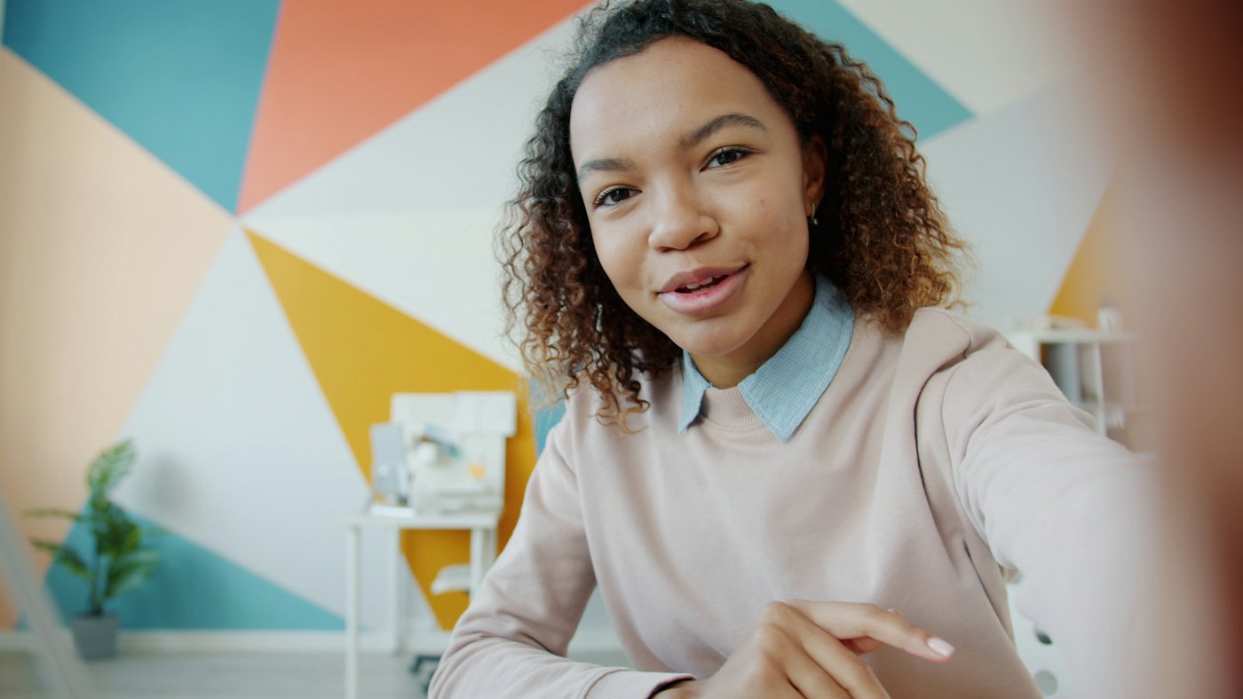Une femme de la diaspora souriante, en appel vidéo depuis chez elle